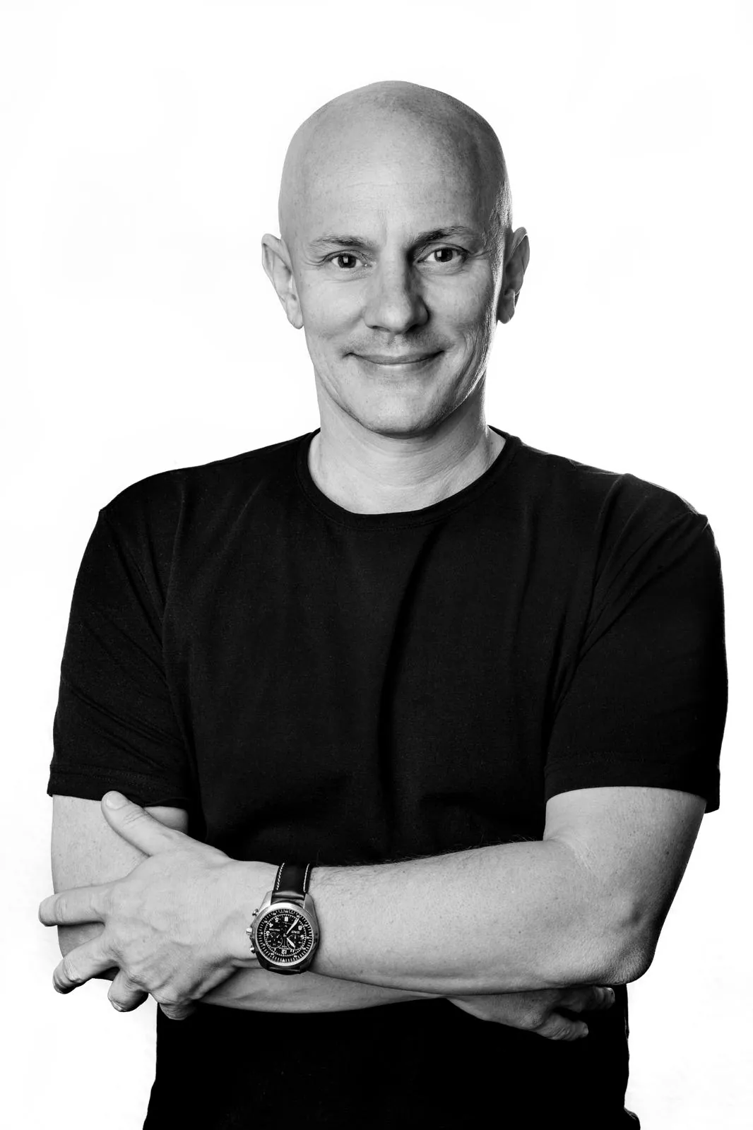 Niko Bellotto, smiling, with his arms crossed. Black-and-white studio portrait.